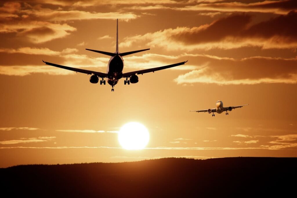 Foto de dois aviões no céu voando durante o pôr-do-sol.